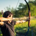 Young archer training with the bow in a city park