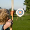Boy taking part in the sporting activity of archery.  Taking aim at the target